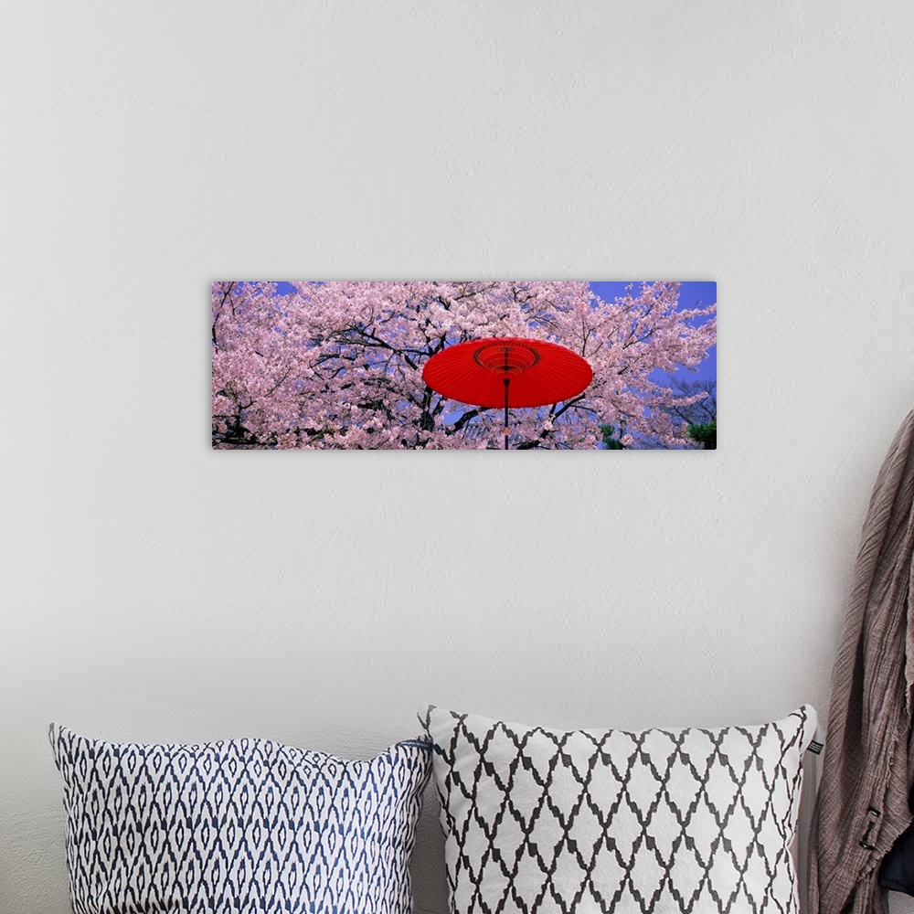 A bohemian room featuring Panoramic wall docor of brightly colored flowering trees with an umbrella in the foreground.