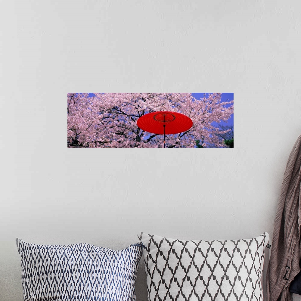 A bohemian room featuring Panoramic wall docor of brightly colored flowering trees with an umbrella in the foreground.