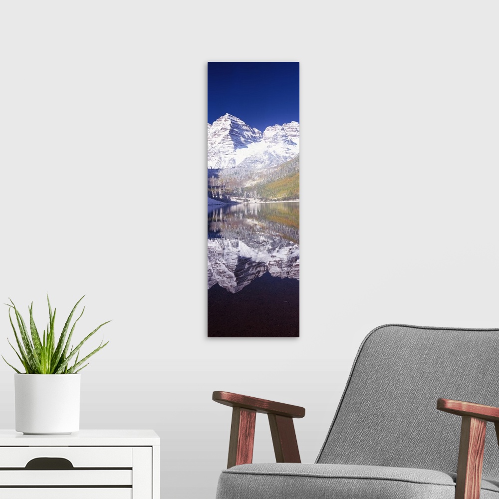 A modern room featuring Vertical panoramic photograph of snow covered mountain that is reflected in the water below.