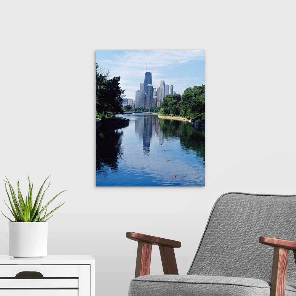 A modern room featuring Vertical panoramic photograph of buildings and skyline reflected in pond lined with trees.
