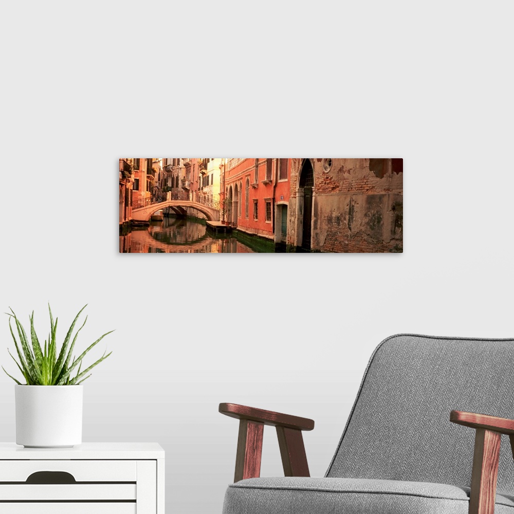 A modern room featuring Panoramic photograph focuses on buildings and bridges following a canal in Venice, Italy.  Locate...