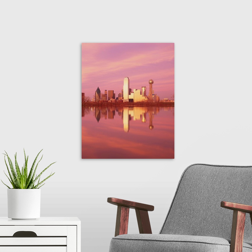A modern room featuring During sunset, the Dallas skyline is photographed from across a body of water that it reflects in.