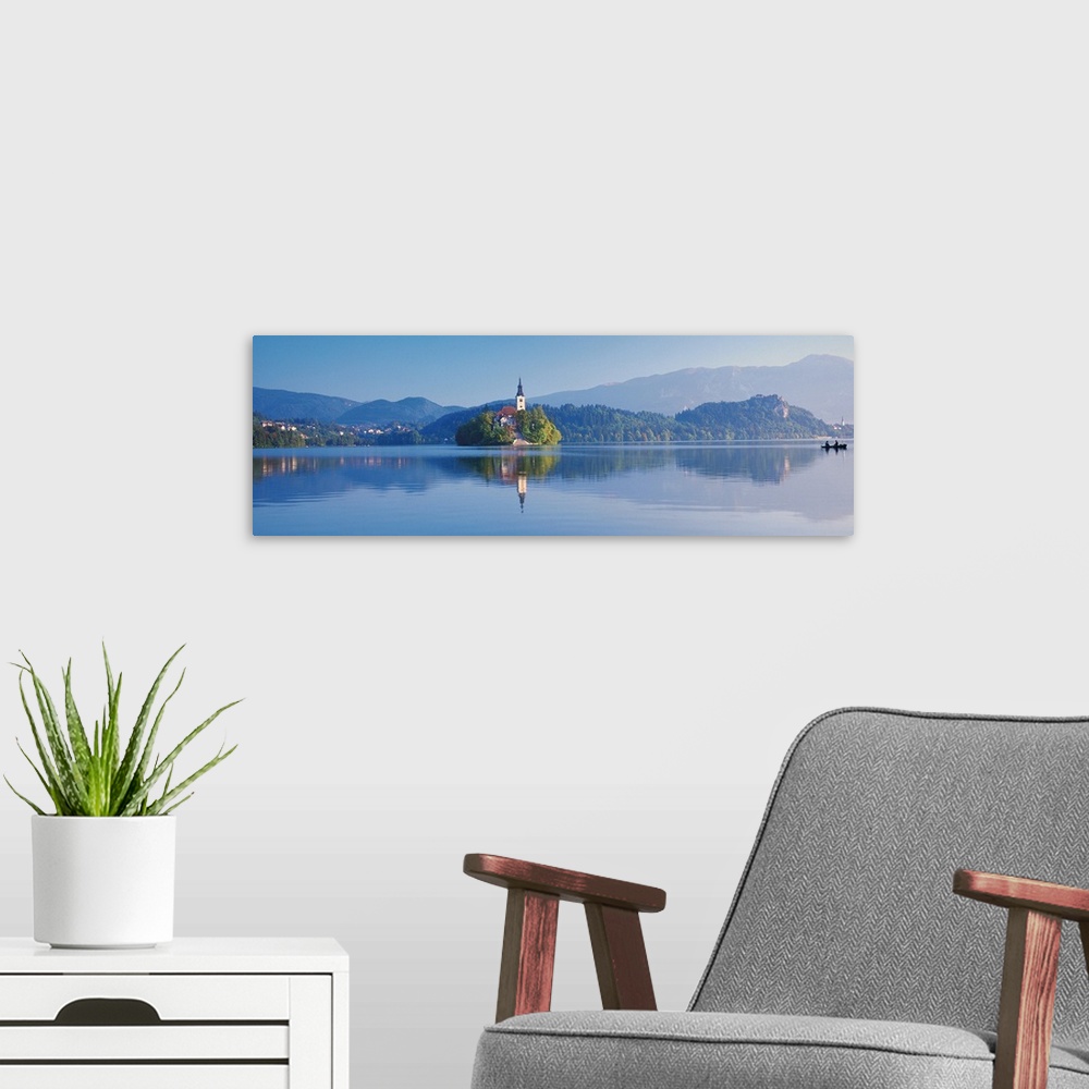 A modern room featuring Giant, horizontal photograph of a mountain landscape and buildings reflecting in the waters of La...