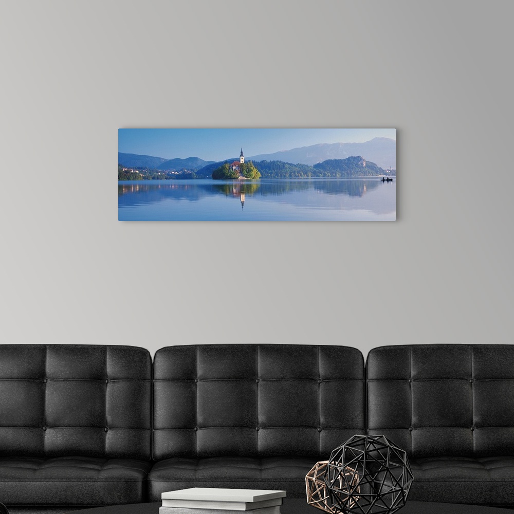 A modern room featuring Giant, horizontal photograph of a mountain landscape and buildings reflecting in the waters of La...
