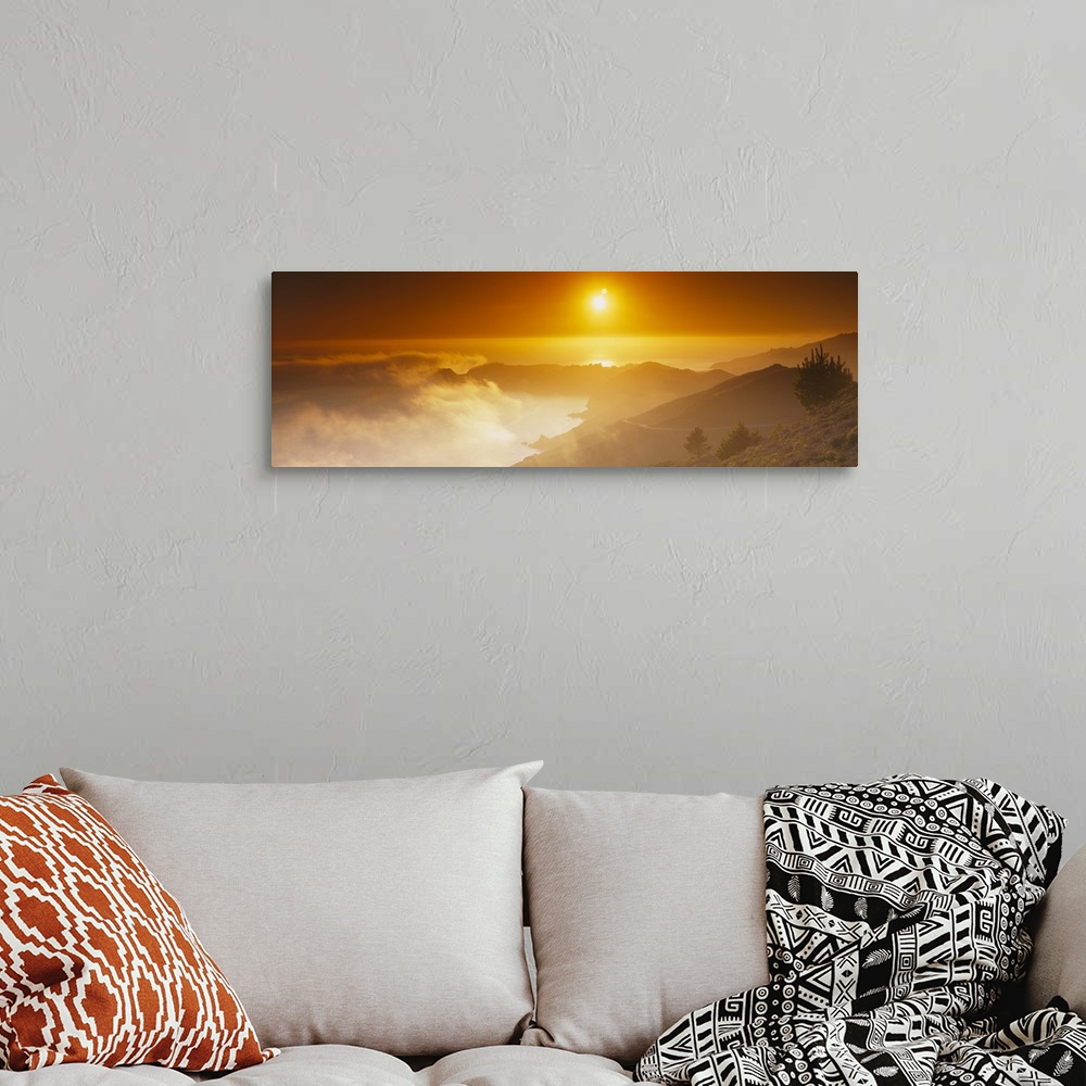 A bohemian room featuring Panoramic photo on canvas of the sun shining bright in the sky above an ocean and mountains with ...