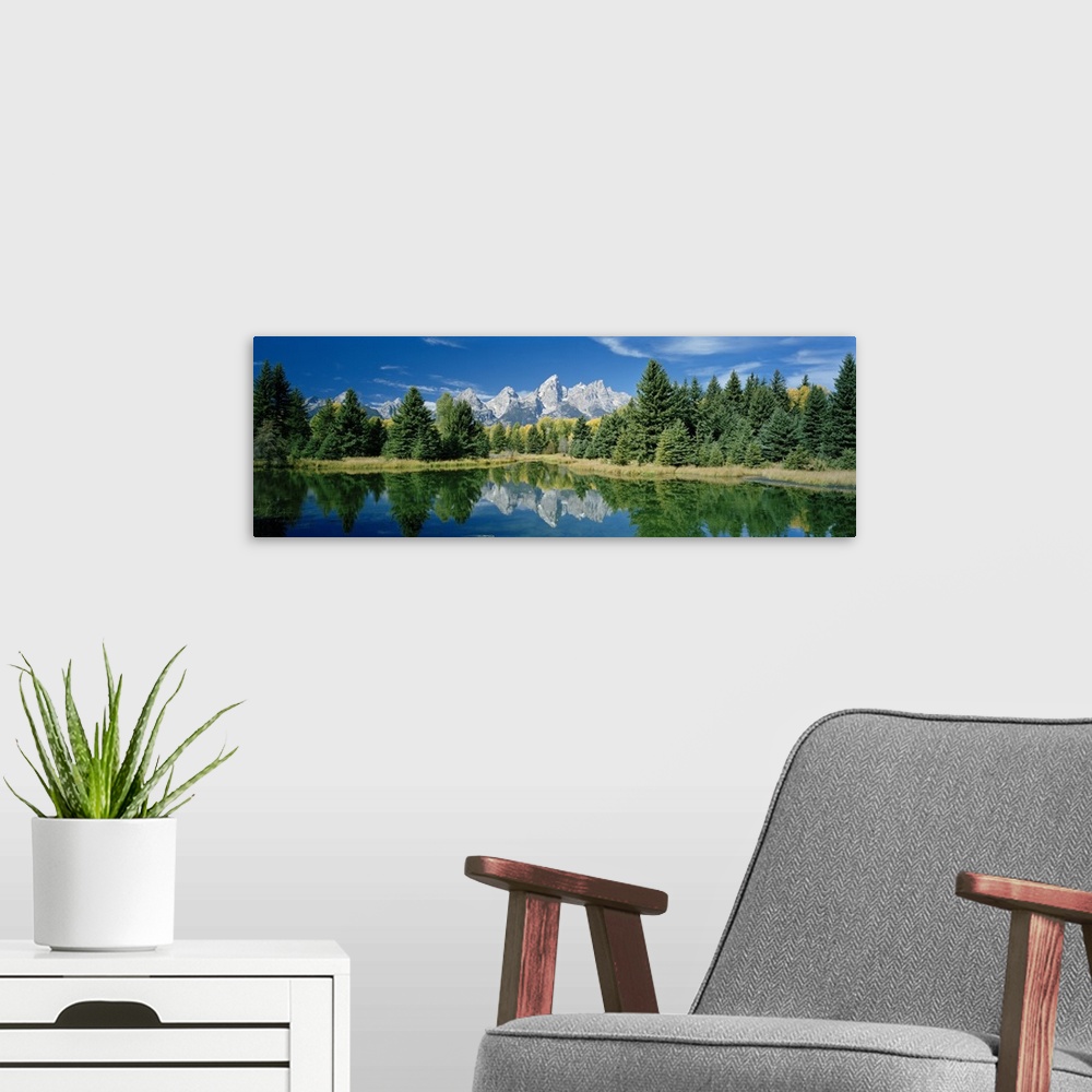 A modern room featuring Panoramic photo print of a water with a reflection of the rugged mountains and forest in the dist...