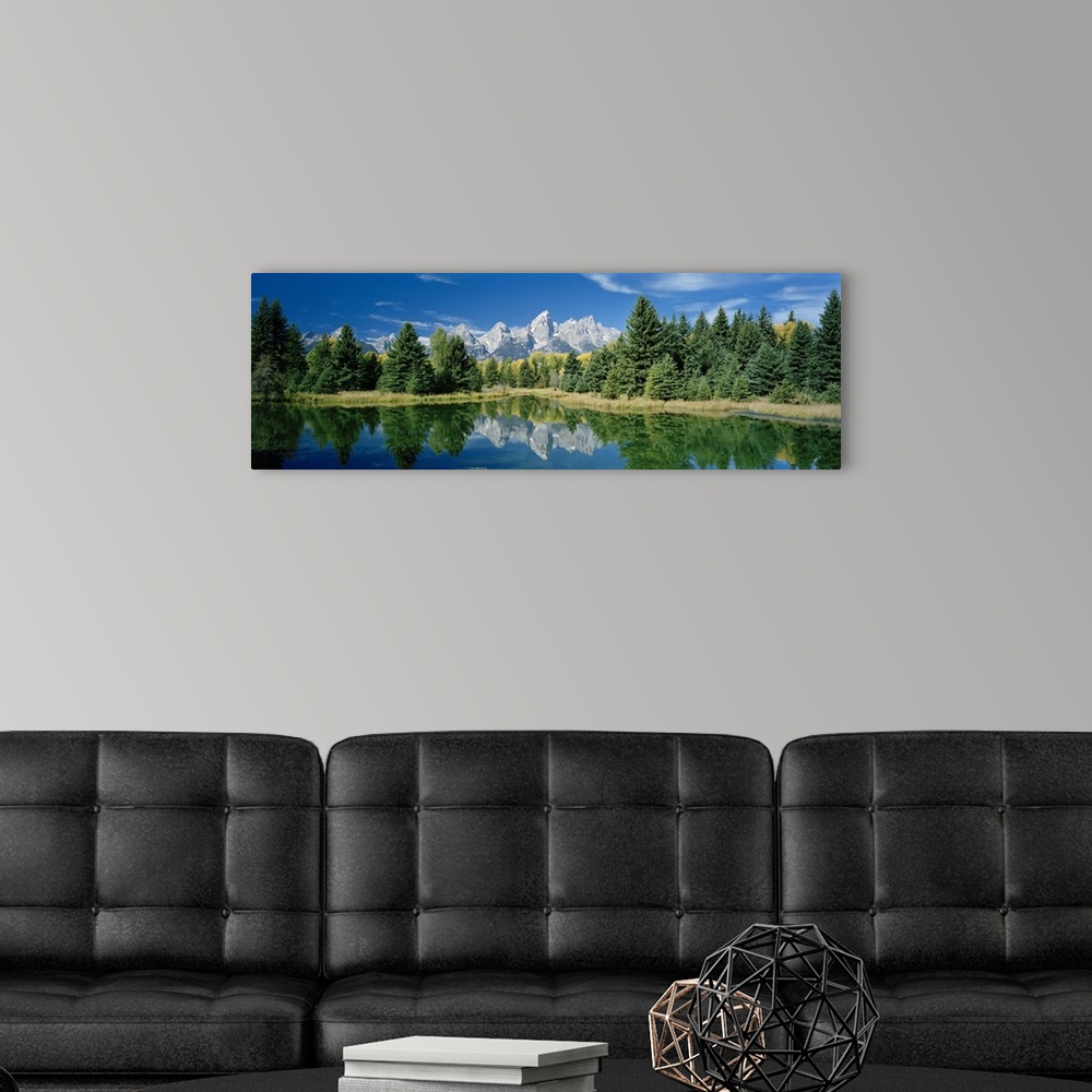 A modern room featuring Panoramic photo print of a water with a reflection of the rugged mountains and forest in the dist...
