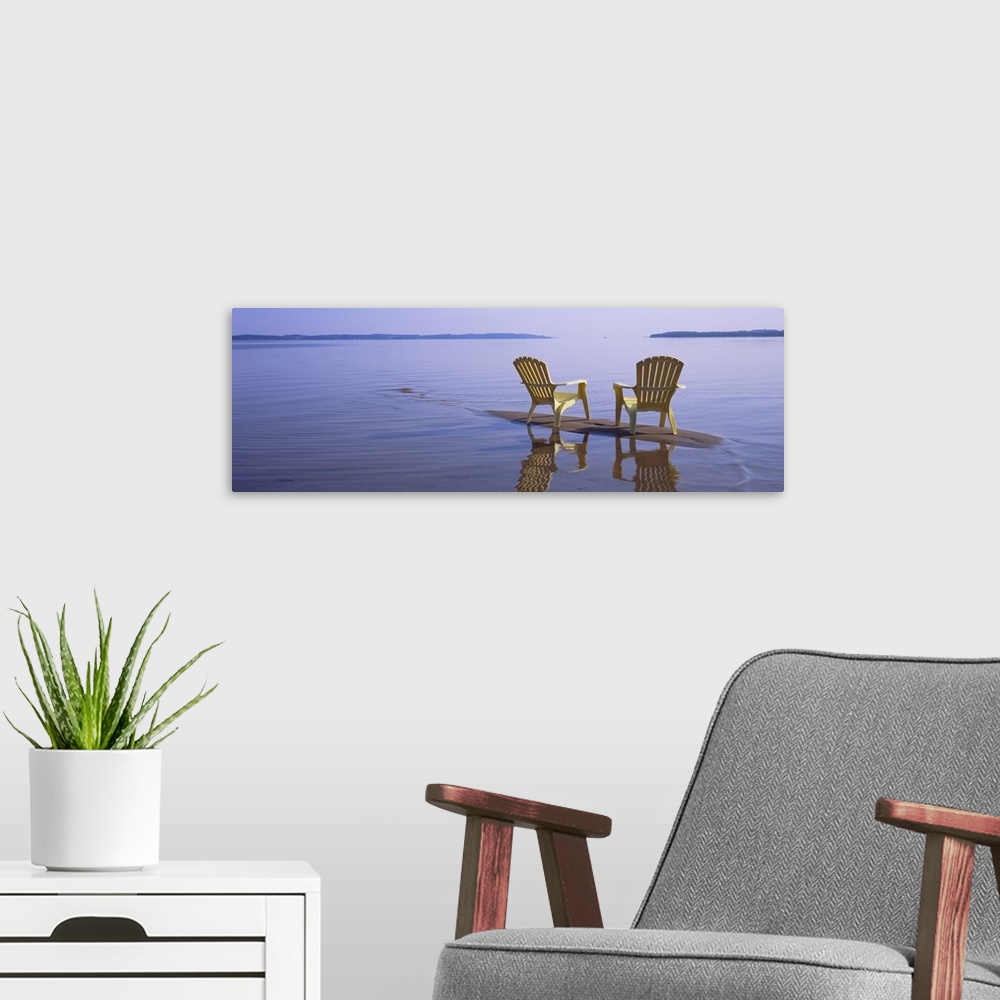 A modern room featuring Panoramic photograph of two beach chairs sitting on top of sand bar with land in the far distance.