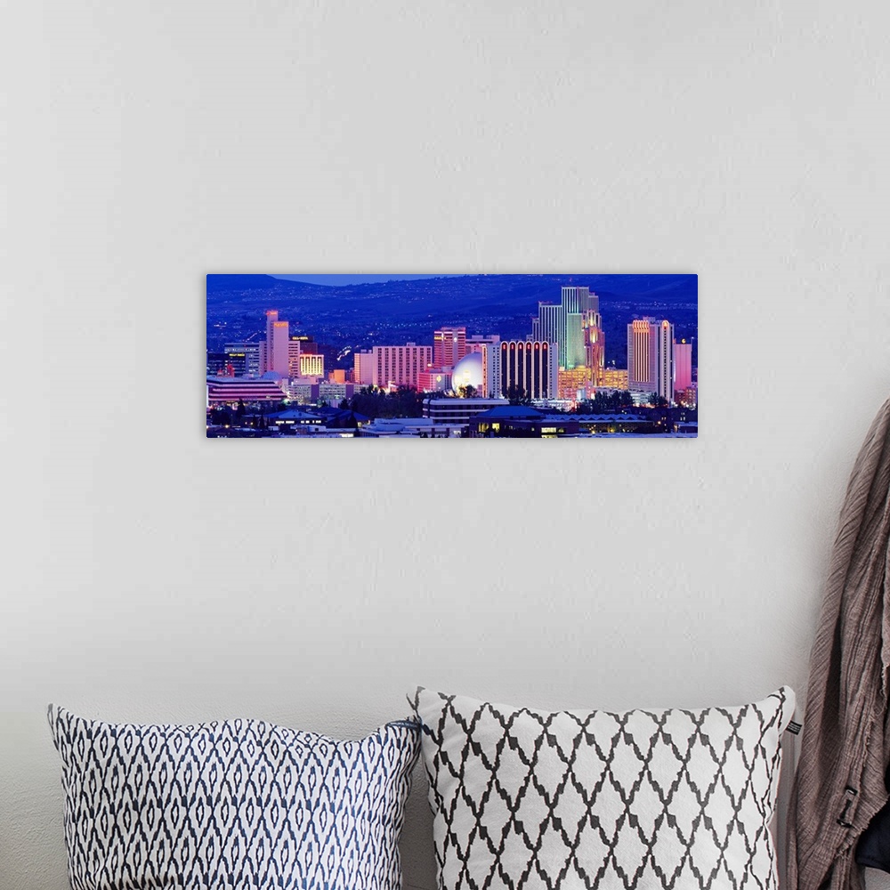 A bohemian room featuring The skyline in Reno is illuminated under a dark sky and photographed in panoramic view.