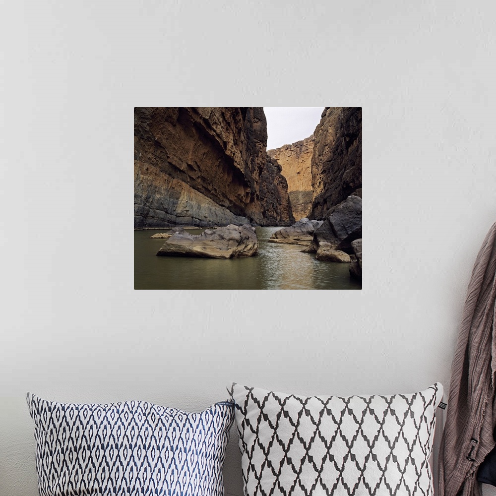 A bohemian room featuring Photo print of a rugged canyon with water flowing by big rocks at the bottom.
