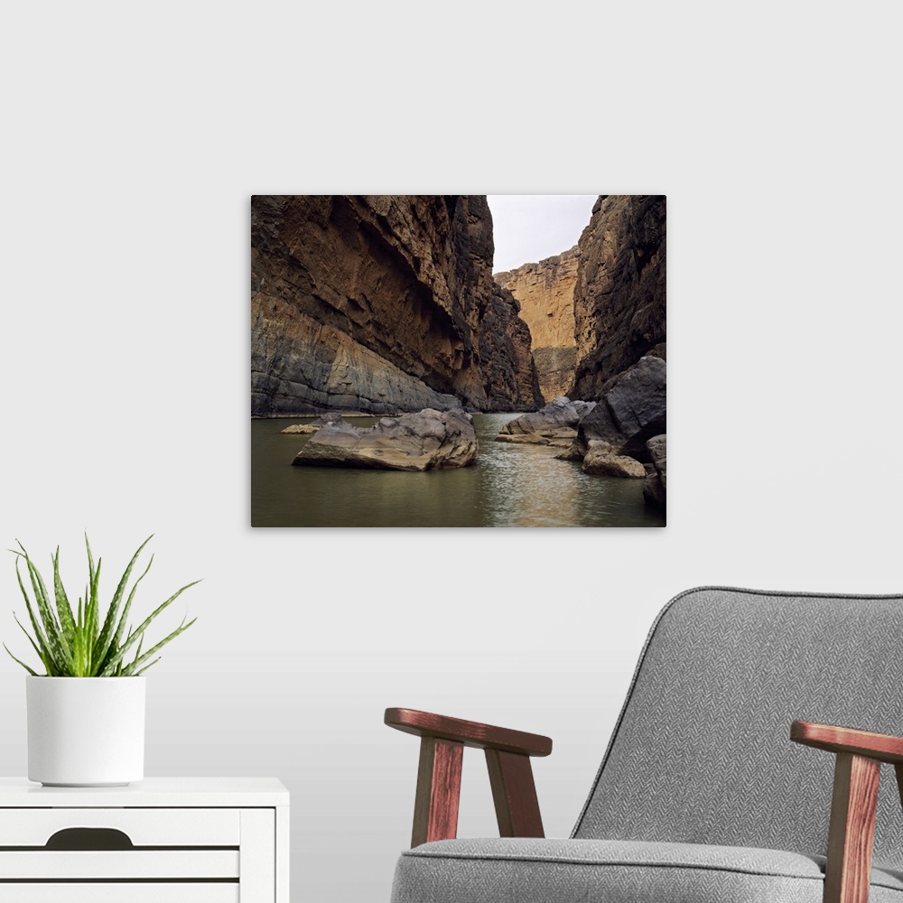 A modern room featuring Photo print of a rugged canyon with water flowing by big rocks at the bottom.