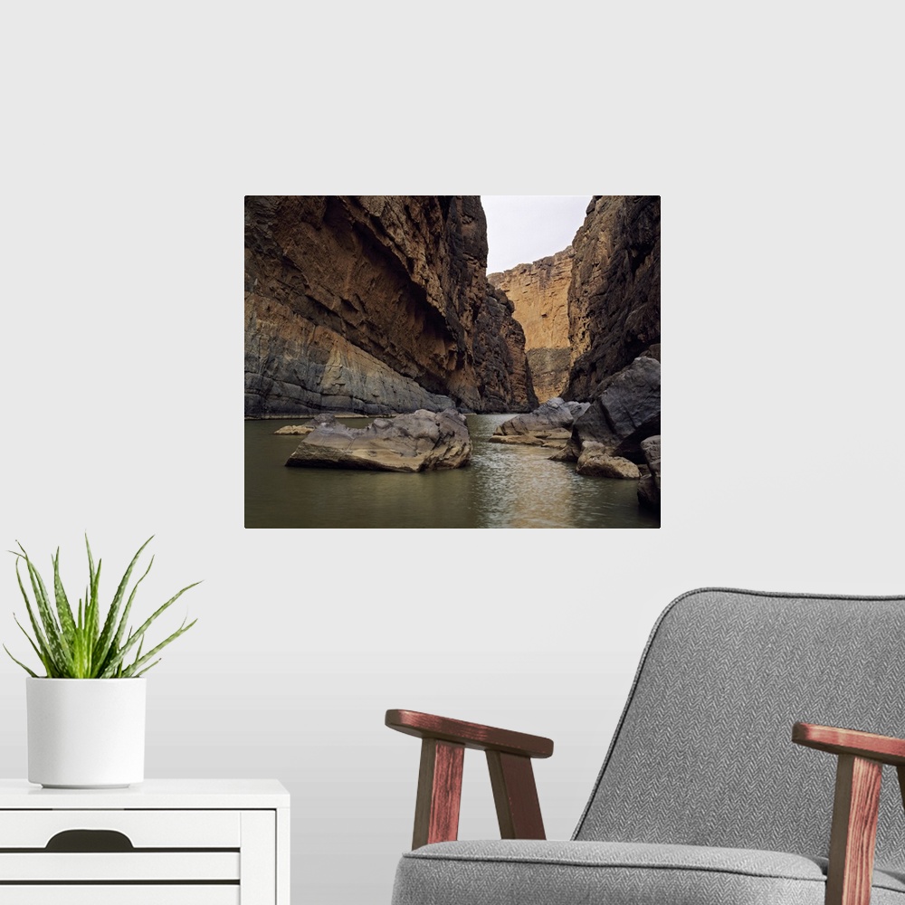 A modern room featuring Photo print of a rugged canyon with water flowing by big rocks at the bottom.