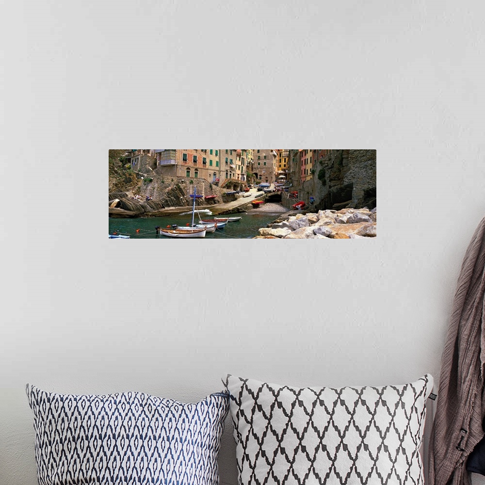 A bohemian room featuring Panoramic photograph showcases a group of small boats sitting and entering an inlet surrounded by...