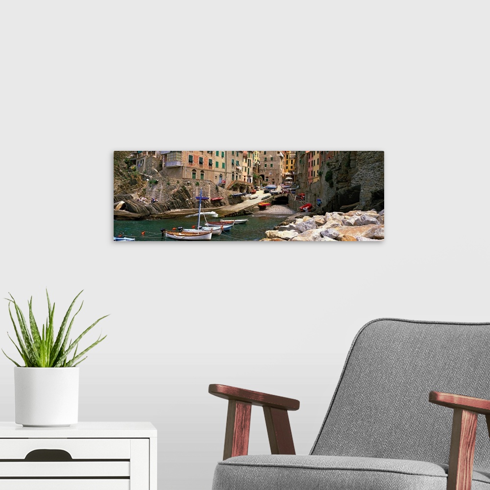 A modern room featuring Panoramic photograph showcases a group of small boats sitting and entering an inlet surrounded by...