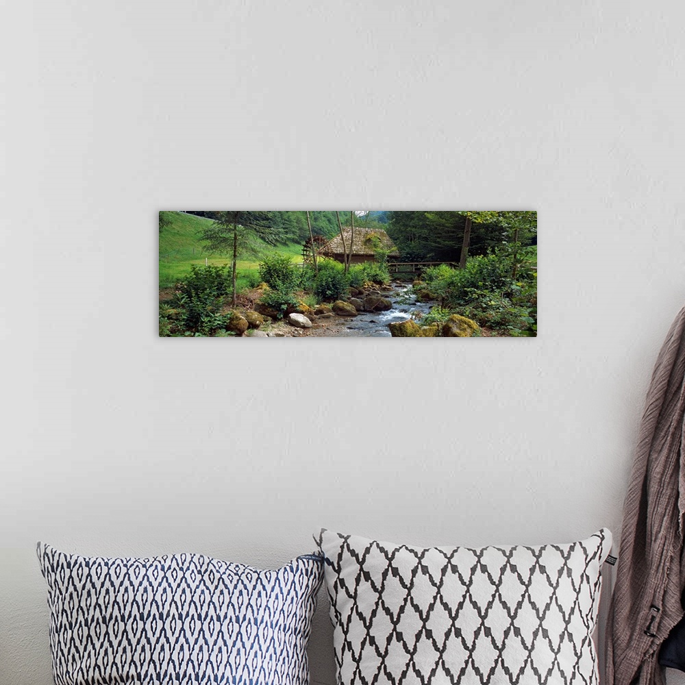 A bohemian room featuring Panoramic wall art of a bucolic scene in this photograph a river filled with moss covered boulder...