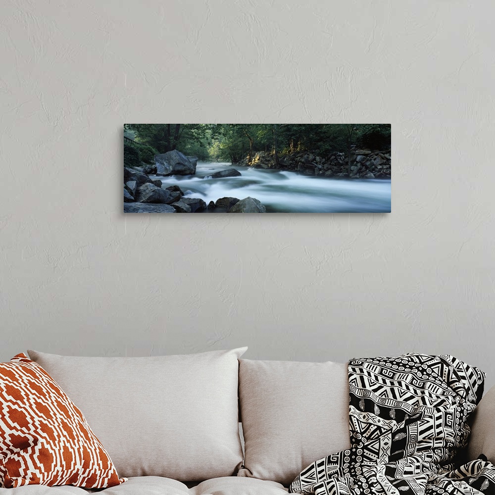 A bohemian room featuring Panoramic photograph of rocky stream lined with forest.