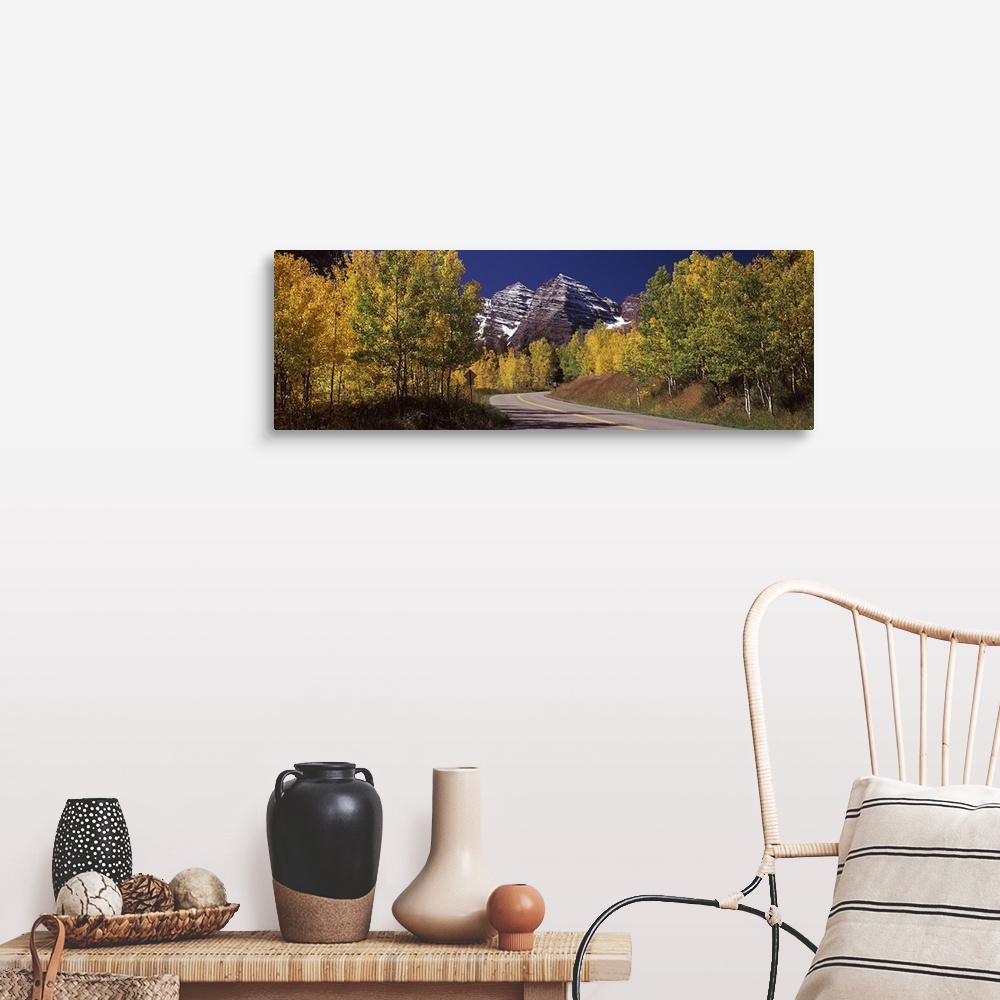 A farmhouse room featuring Large, horizontal photograph of a road winding through a fall colored forest, the Maroon Bells in...