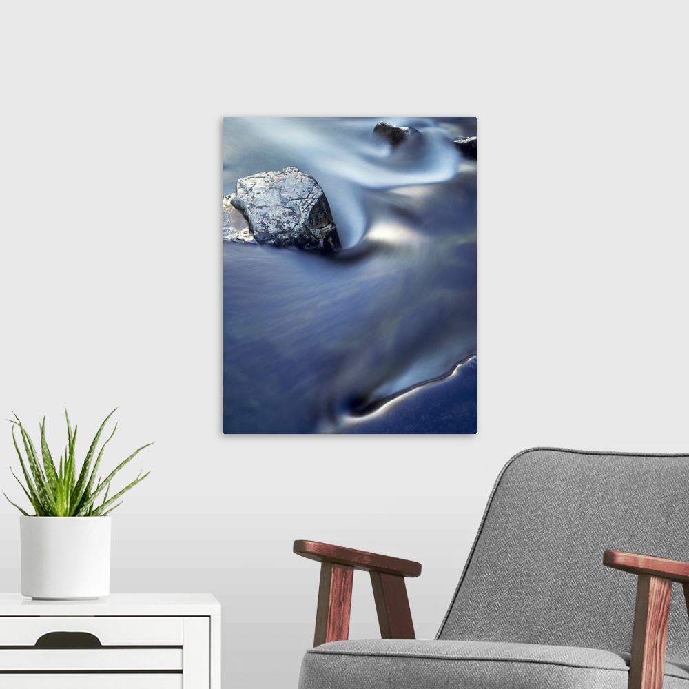 A modern room featuring Vertical, close up photograph on a large wall hanging  of blurred water in rapid movement as it s...