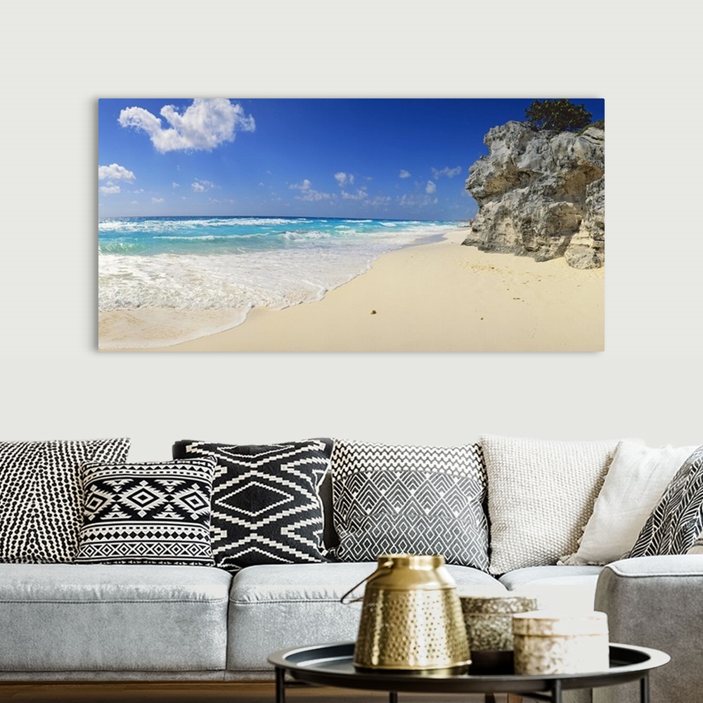 A bohemian room featuring Panoramic photograph of beach with huge rock structure with tree on top.  Waves and sea foam and ...