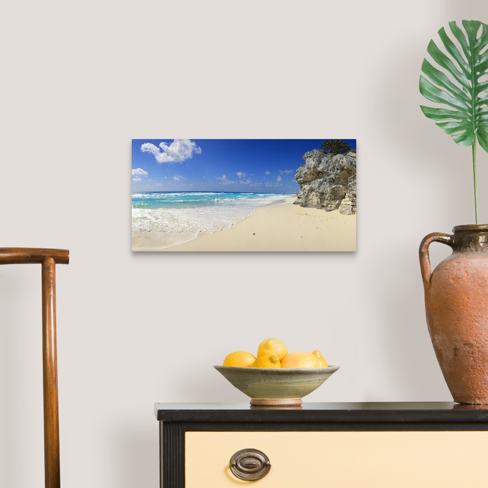 A traditional room featuring Panoramic photograph of beach with huge rock structure with tree on top.  Waves and sea foam and ...