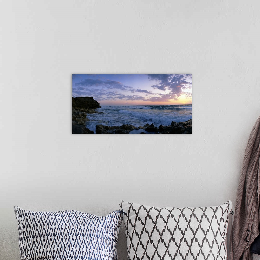 A bohemian room featuring Oversized artwork of a photograph looking out into the ocean as waves crash onto the rock formati...