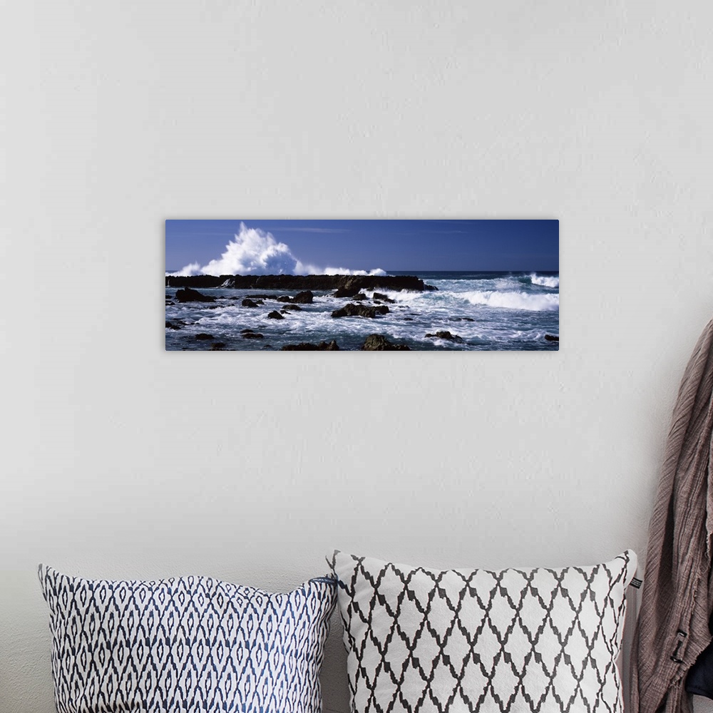 A bohemian room featuring Panoramic photograph of rocks at sea with waves crashing around them under a clear sky.