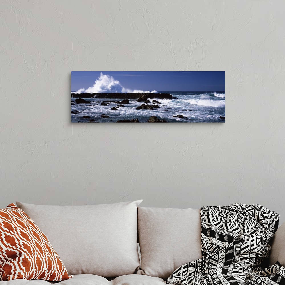 A bohemian room featuring Panoramic photograph of rocks at sea with waves crashing around them under a clear sky.