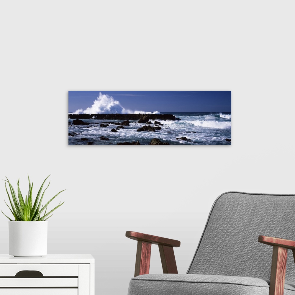 A modern room featuring Panoramic photograph of rocks at sea with waves crashing around them under a clear sky.