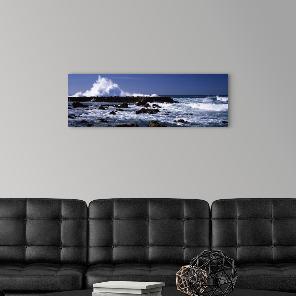 A modern room featuring Panoramic photograph of rocks at sea with waves crashing around them under a clear sky.