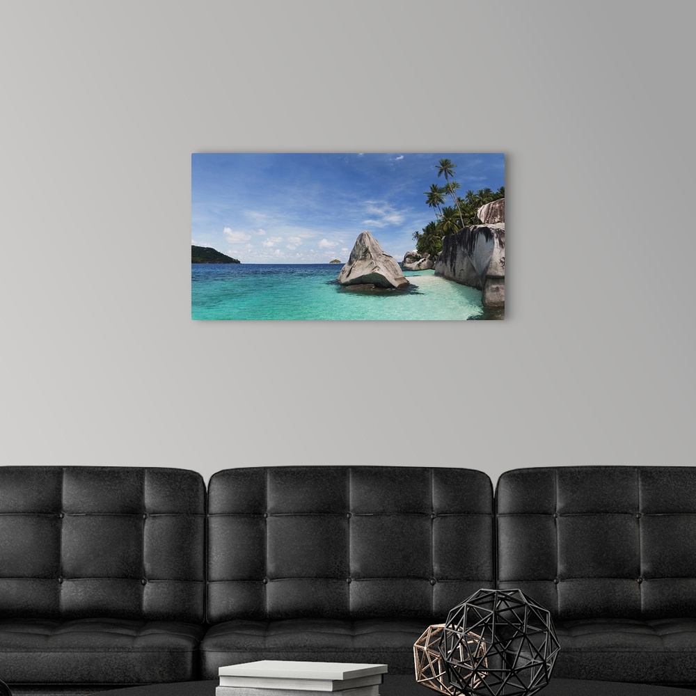 A modern room featuring Landscape photograph on a large canvas of clear blue waters in Malaysia, along the rocky shorelin...