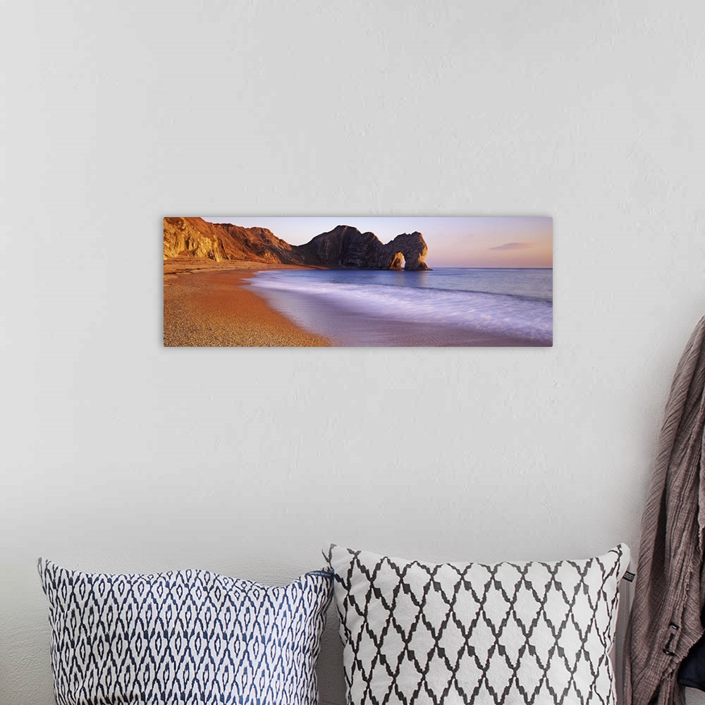 A bohemian room featuring Panoramic photograph of beach with large stone formations in distance.