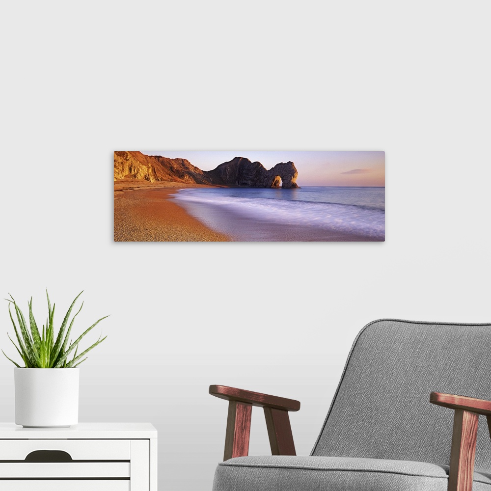 A modern room featuring Panoramic photograph of beach with large stone formations in distance.