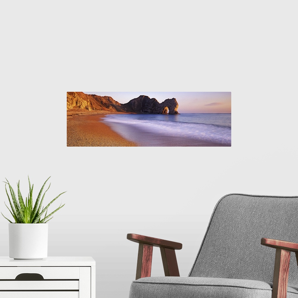 A modern room featuring Panoramic photograph of beach with large stone formations in distance.