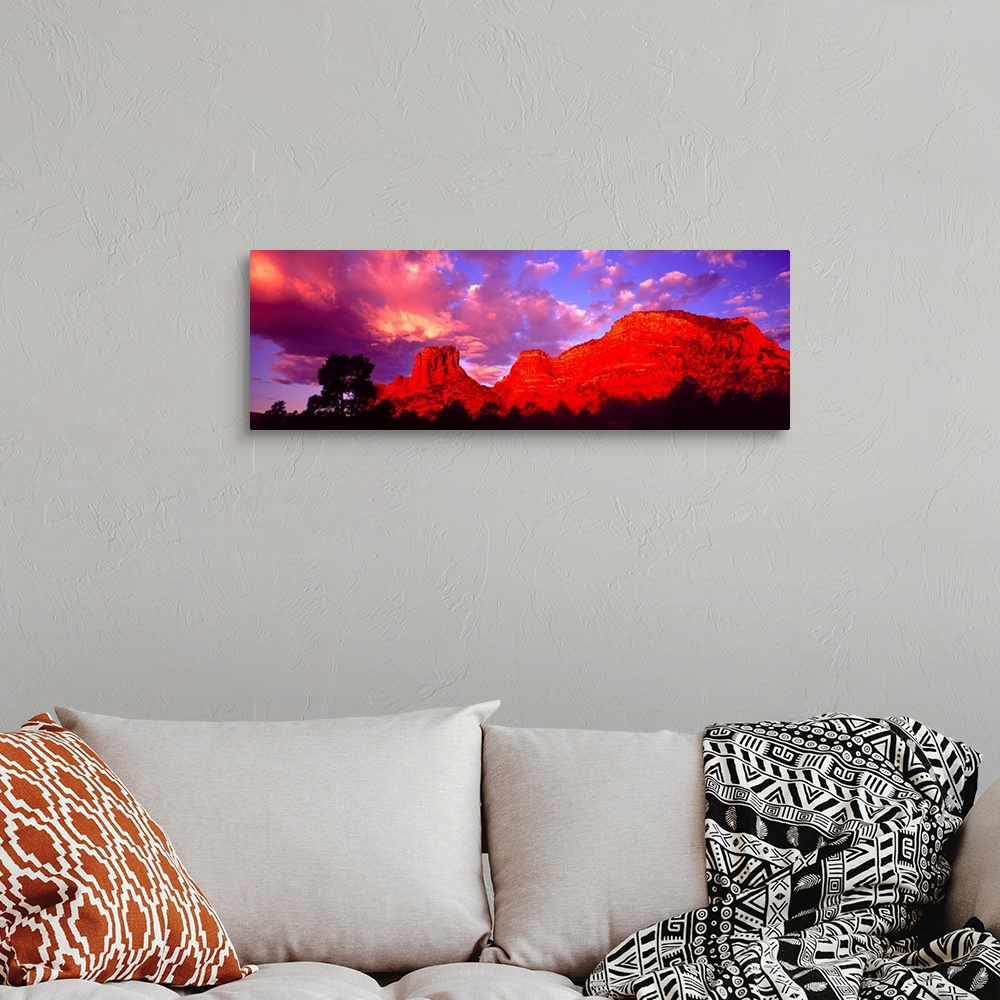 A bohemian room featuring Wide angle photograph on a large canvas of a giant rock formation beneath a vibrant sky at sunset...