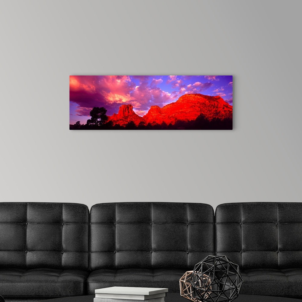 A modern room featuring Wide angle photograph on a large canvas of a giant rock formation beneath a vibrant sky at sunset...
