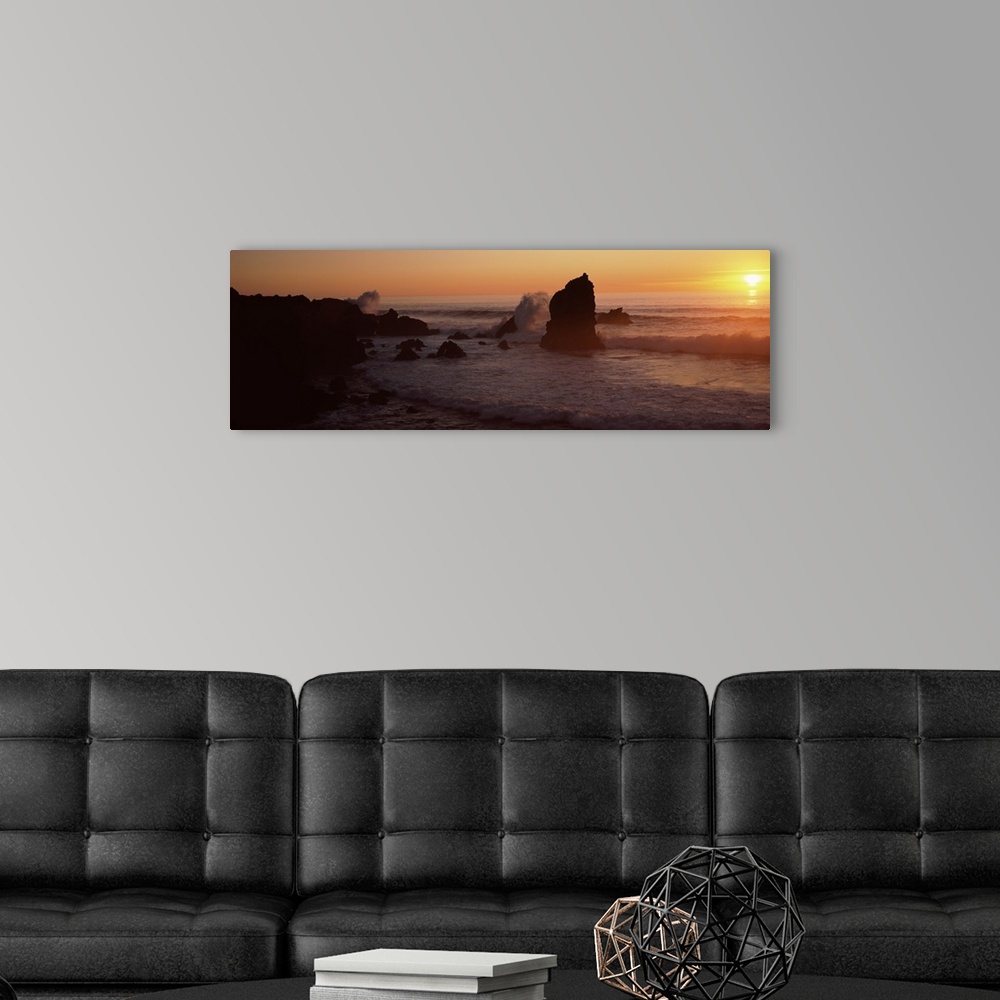 A modern room featuring Panoramic photo on canvas of rock formations on a beach with waves breaking on the shore at sunset.