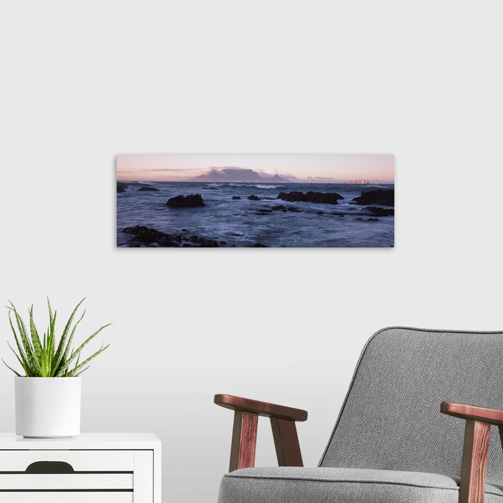 A modern room featuring Rocks in the sea with Table Mountain in the background, Bloubergstrand, Table Mountain, Cape Town...