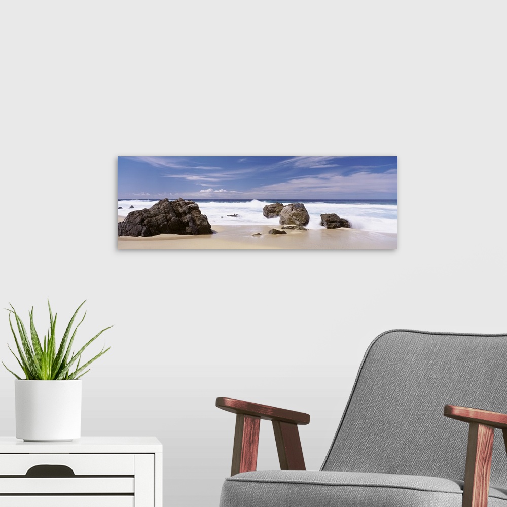 A modern room featuring Oversized, horizontal photograph of the big waves of the Pacific Ocean rushing onto a shore with ...