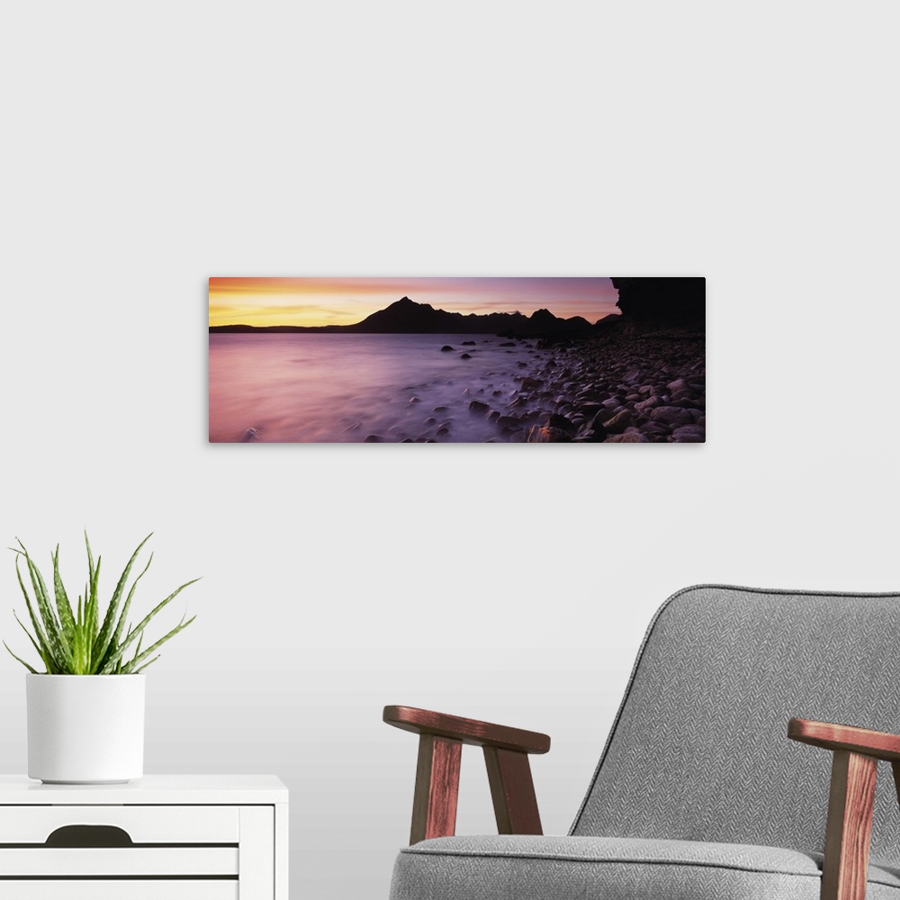 A modern room featuring Panoramic photograph of pebble covered shoreline rising from mist with mountain silhouette in the...