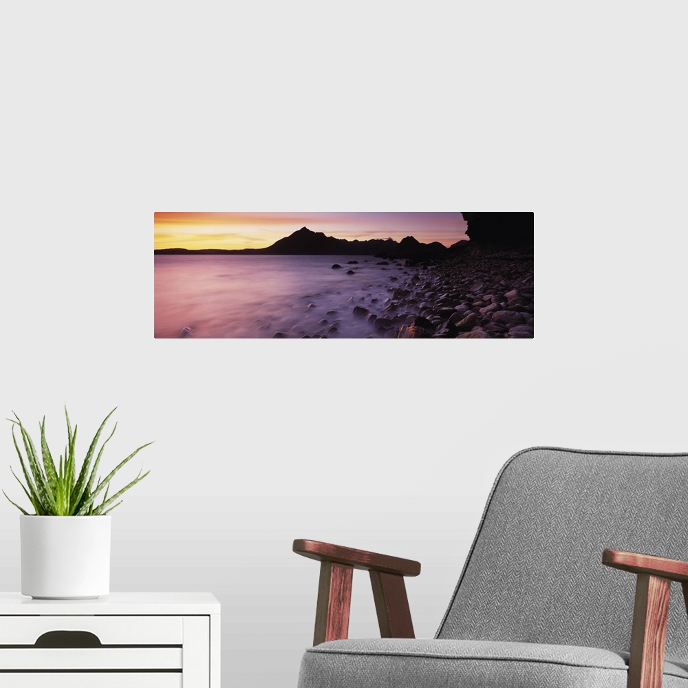 A modern room featuring Panoramic photograph of pebble covered shoreline rising from mist with mountain silhouette in the...