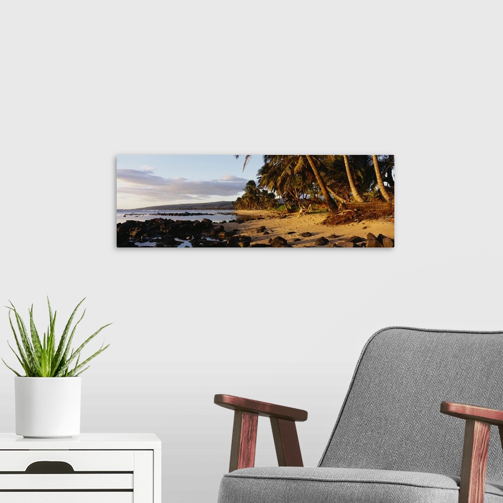 A modern room featuring This decorative wall art is a panoramic photograph of sunset on a tropical beach covered with vol...
