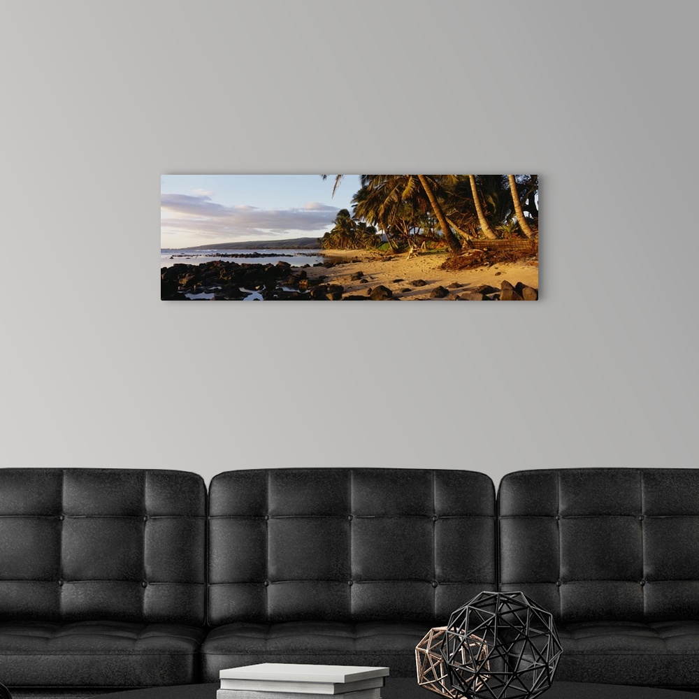 A modern room featuring This decorative wall art is a panoramic photograph of sunset on a tropical beach covered with vol...