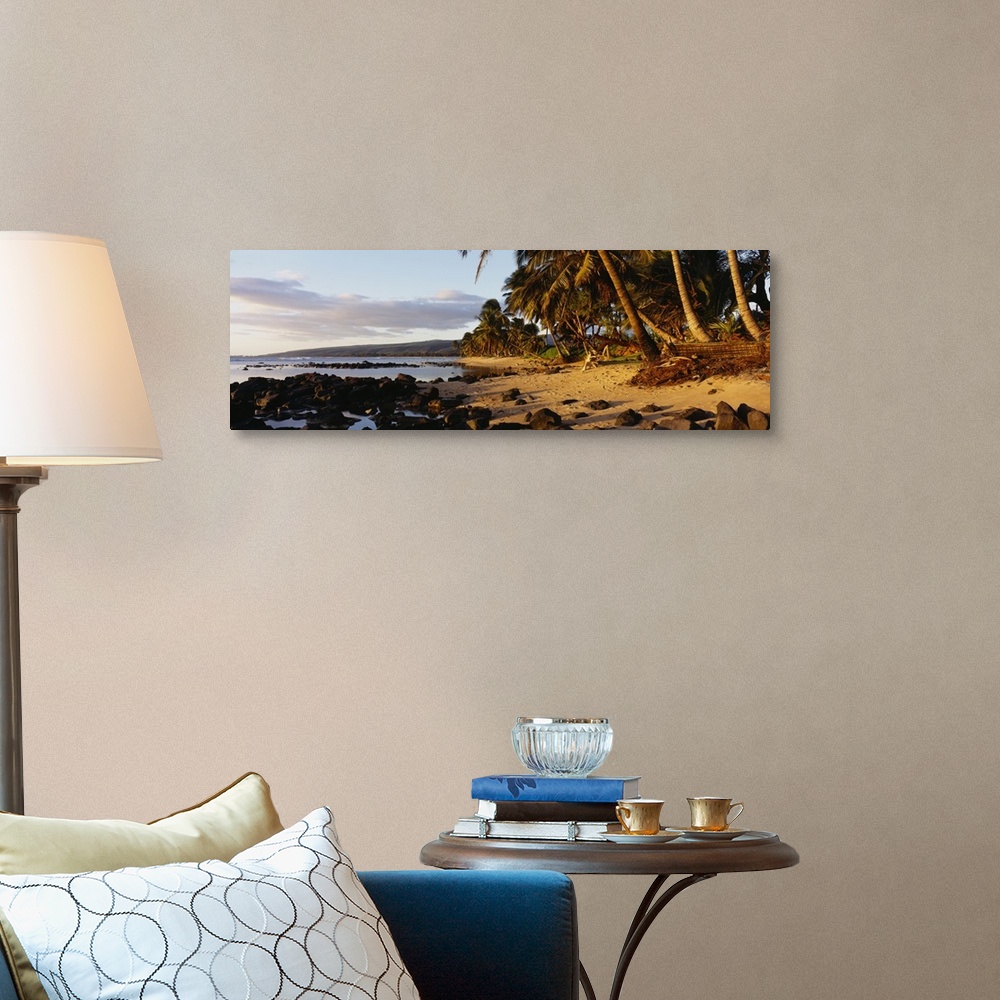 A traditional room featuring This decorative wall art is a panoramic photograph of sunset on a tropical beach covered with vol...