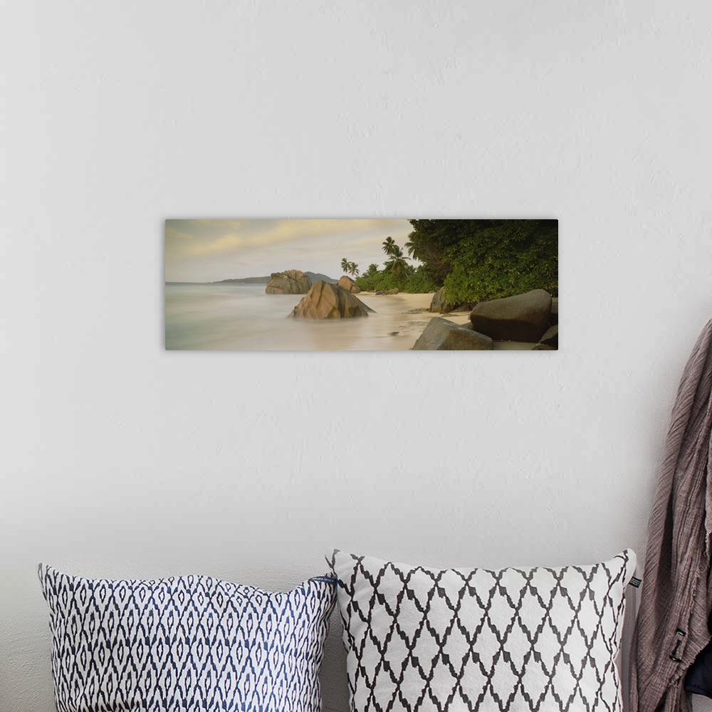 A bohemian room featuring This large panoramic photograph shows a beach with lush green forest behind it and rocks sitting ...