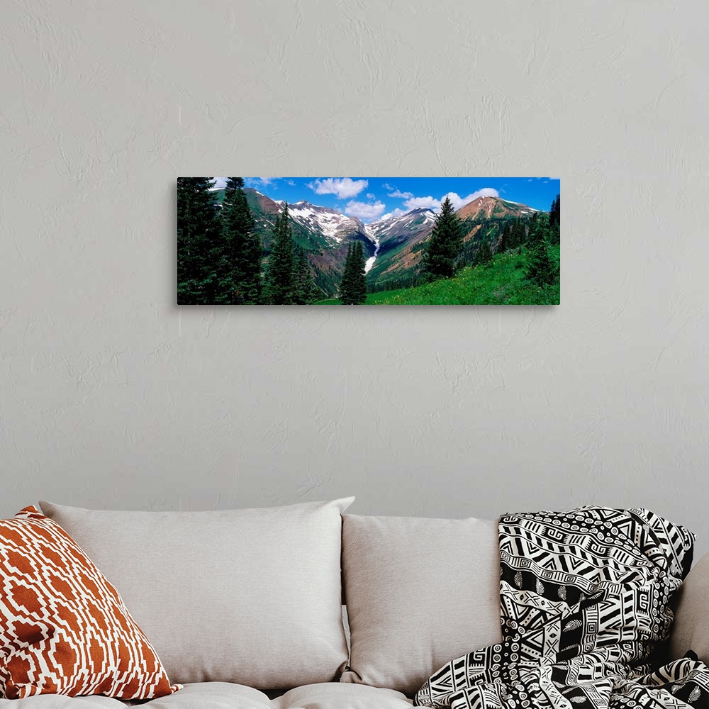 A bohemian room featuring This panoramic photograph taken from the side of a mountain looks across a valley to the snowcapp...