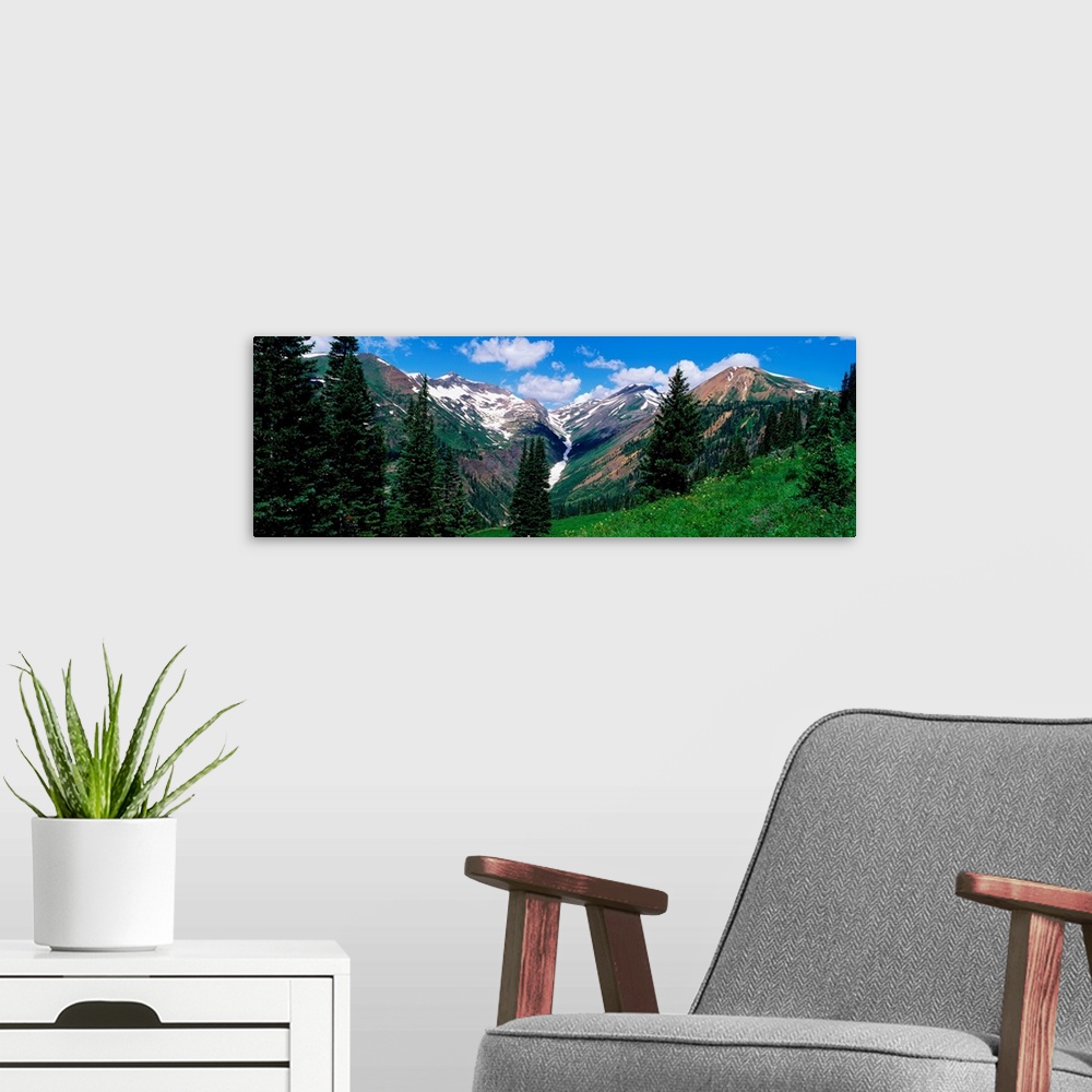 A modern room featuring This panoramic photograph taken from the side of a mountain looks across a valley to the snowcapp...