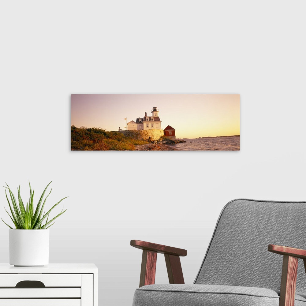 A modern room featuring Panoramic photograph on a big canvas of the Rose Island lighthouse overlooking the water at sunse...