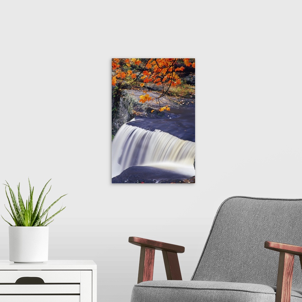 A modern room featuring Peaceful scene of a waterfall in a New England forest in the fall, with a rocky cliff and bright ...