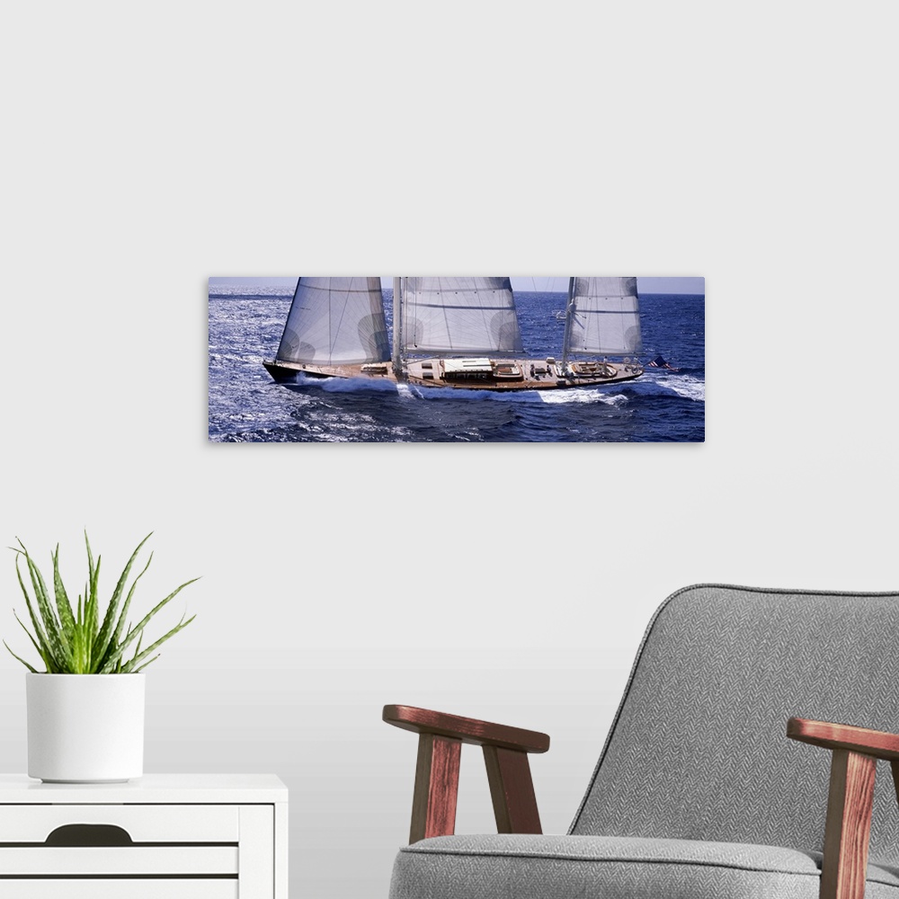 A modern room featuring Large, horizontal photograph of a sailboat, slightly tilting as it charges through the blue water...