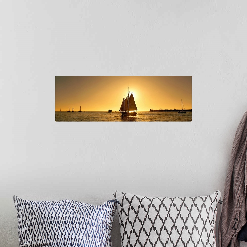 A bohemian room featuring A sail boat with multiple masts photographed at sunset it in the Florida Keys on panoramic wall art.